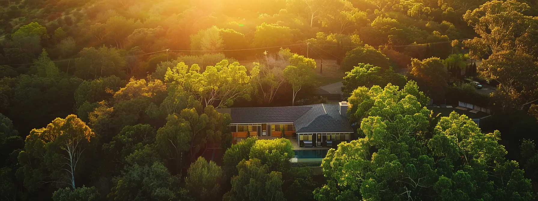 a stunning aerial shot of a modern, spacious home surrounded by lush greenery and bathed in golden sunlight, perfect for an instagram campaign for home builders.