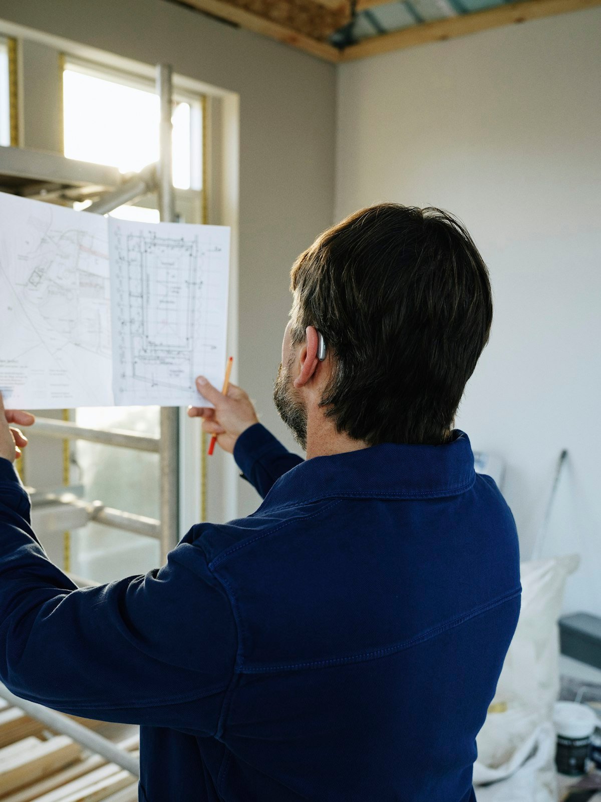 North American general contractor reviewing blueprints at a residential construction site