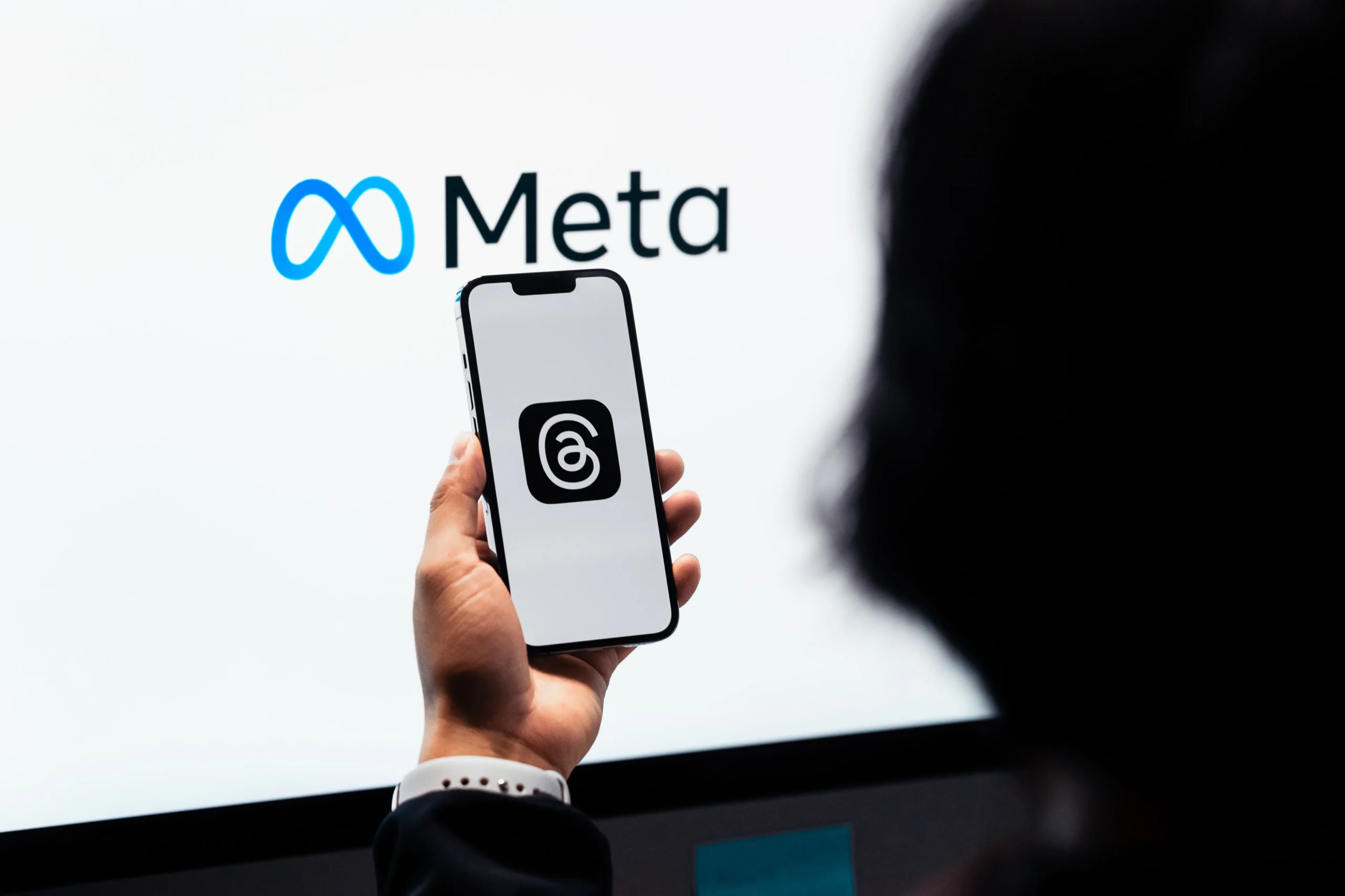 The Meta Ads Process That Fills Custom Builder Calendars 1 Hands holding smartphone with Meta Threads logo on screen, Meta branding in background.